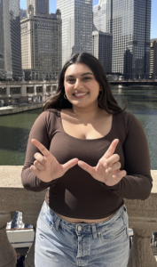 A woman smiling while making the Wisconsin logo with her hands. 